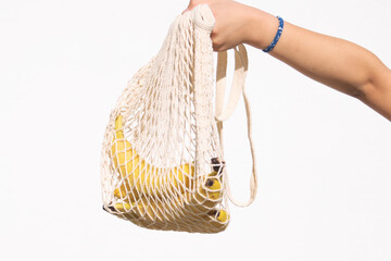 Obraz premium a teenage girl holds bananas in a net on a white background,