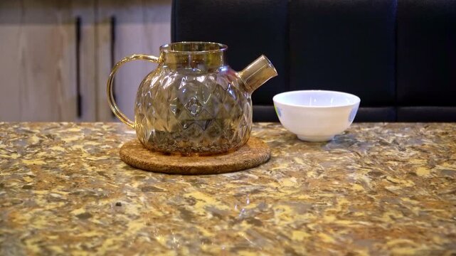 Closeup woman brewing tea in teapot at kitchen table, adding tea leaves and pouring hot water from electric kettle, performing qaytarma by pouring into bowl and back, authentic traditional video