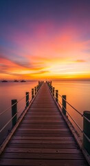 Fototapeta premium A serene wooden pier extends into a vibrant sunrise over calm water, showcasing a tranquil and peaceful atmosphere.