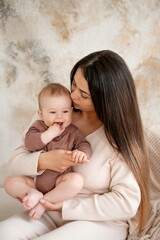 mom and baby, maternal love and care, a mother holds a baby in her arms, gently kissing and hugging him at home, a mother with a small child on maternity leave