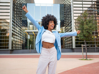 Happy businesswoman celebrating success outside office building
