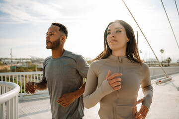 Male and female athletes running near fence and looking ahead