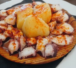 galician octopus with potatoes, paprika, salt and olive oil. typical Spanish Galician tapa, on a traditional wooden plate
