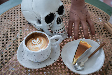 Close up of Hot coffee latte with latte art milk foam in cup mug and Homemade burnt cheesecake with decor in a coffee a theme of halloween on wood desk Halloween holiday background.