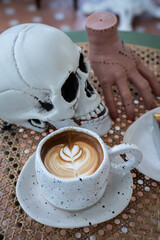 Close up of Hot coffee latte with latte art milk foam in cup mug and Homemade burnt cheesecake with decor in a coffee a theme of halloween on wood desk Halloween holiday background.