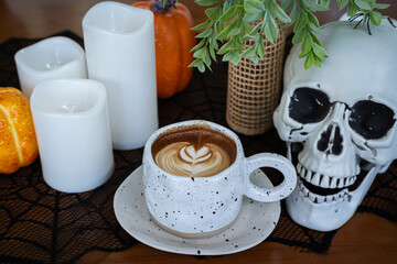 Halloween celebrated coffee,Close up of Hot coffee latte with latte art milk foam in cup mug with decor in a coffee a theme of halloween on wood desk Halloween holiday background.