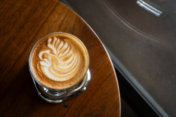 Hot coffee latte with latte art milk foam in cup mug on wood desk on top view. As breakfast In a coffee shop at the cafe,during business work concept,vintage style