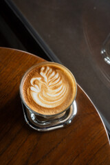 Hot coffee latte with latte art milk foam in cup mug on wood desk on top view. As breakfast In a coffee shop at the cafe,during business work concept,vintage style