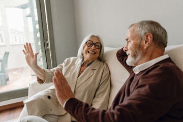 A woman is smiling and looking at a man while they are sitting on a couch with their arms raised to the side