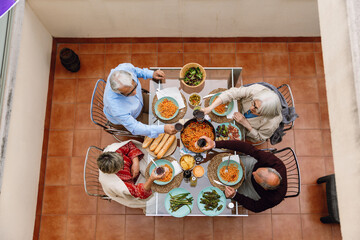 A group of four friends are sitting at a table and about to clink glasses