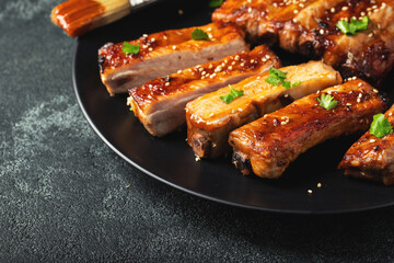 Hot grilled spare ribs from a summer BBQ served on a plate with sauce. Top view. Copy space