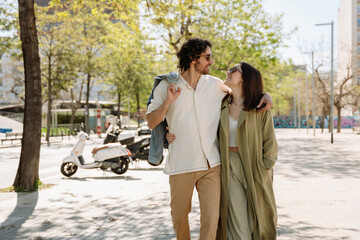 A man and woman hug and smile as they walk and look at each other