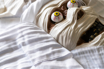 Spooky mummy head mask and costume featuring exaggerated cartoonish eyes and bandages, with copy space on bandages, ideal for Halloween celebrations or themed events.