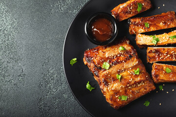 Hot grilled spare ribs from a summer BBQ served on a plate with sauce. Top view. Copy space