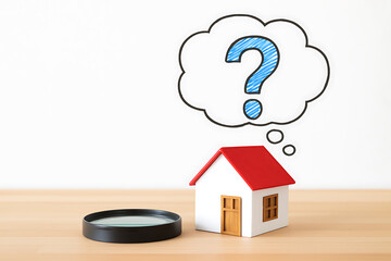 Real estate uncertainty concept with house model magnifying glass and question mark symbolizing housing search and market doubts