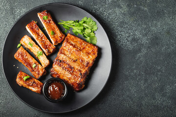 Hot grilled spare ribs from a summer BBQ served on a plate with sauce. Top view. Copy space