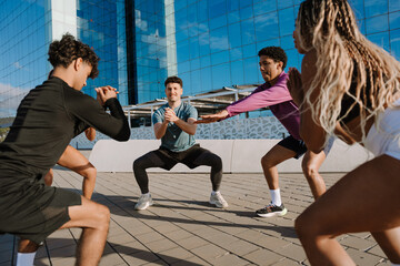 A group of five athletes doing squats in a circle
