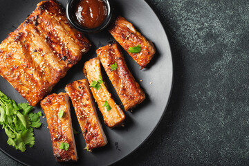 Hot grilled spare ribs from a summer BBQ served on a plate with sauce. Top view. Copy space