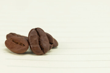 Macro of roasted coffee beans on lined paper. Aromatic background for cafe menu or recipe