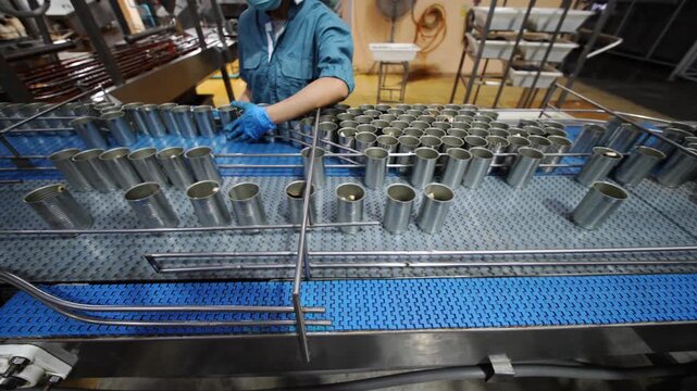 Canning Process: A close-up view of a factory assembly line where metal cans are processed and prepared for filling, showcasing the efficiency of modern food production.