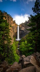 Majestic waterfall cascading down a rocky mountainside, surrounded by lush green forest