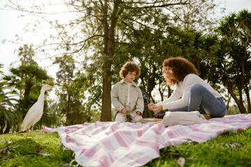 The son looks at his mother's hands, which hold their fingers together and smile while they sit on...