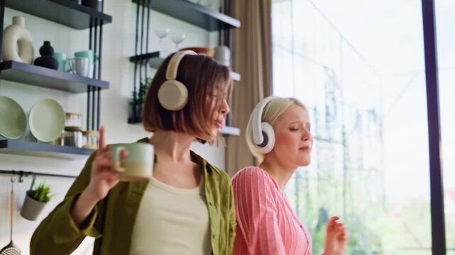 Cooking roommates dancing kitchen closeup. Blonde brunette headphones having fun