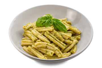 Caserecce pasta topped with pesto sauce and basil leaves on a white plate isolated