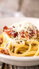 Close-up of pasta dish with bacon, cheese, and pepper