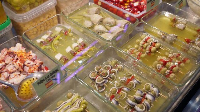 Trays of tapas salads and olives, serving spoons resting on pans at the Central Market of Valencia, Spain