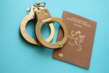 Luxembourg passport with police handcuffs on table. Criminal level and arrests in Europe