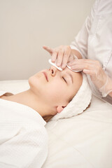 Young caucasian female receiving facial treatment at spa with therapist in white coat.