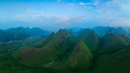 A breathtaking aerial view of a lush green valley surrounded by towering mountains. A winding river...