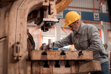 Fototapeta premium Senior experienced technician checking and maintenance a large machine in metal sheet factory