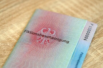 German temporary Permanent resident card lies on wooden table. Fiktionsbescheinigung