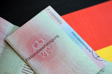 German temporary Permanent resident card lies on Germany flag. Fiktionsbescheinigung