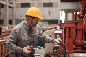 Senior experienced technician checking large machine gears on a production line