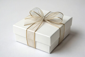 Obraz premium Birthday Background White Gift Box Tied with Sheer Gold Ribbon and Bow on a White Background present paper