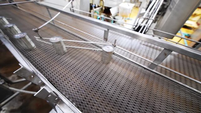 Automated Beverage Canning Line: A high-speed conveyor belt system transports aluminum cans on a production line in a modern beverage factory, showcasing automated industrial process.