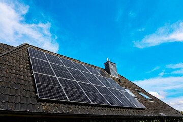 Fototapeta premium Photovoltaic panels providing green energy on a rooftop under blue sky