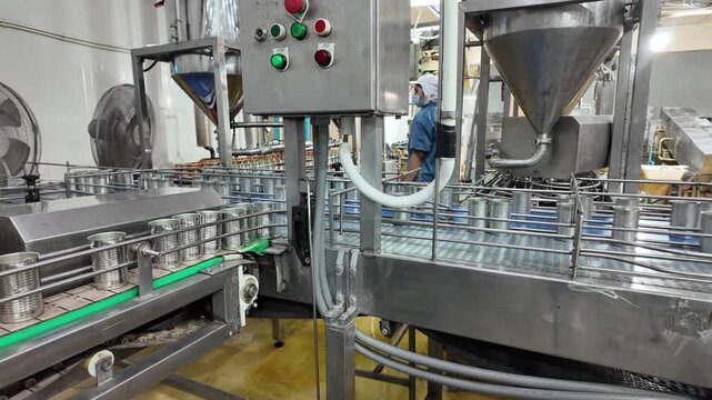 Canning Factory Conveyor Line: Automated conveyor belts in a food processing plant move rows of cans, showcasing modern food production and industrial efficiency.