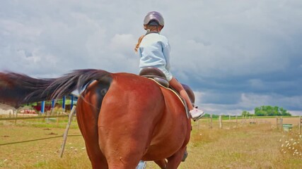 Little cute girl is riding horse in a helmet, training and practicing