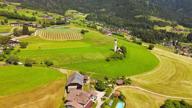 Chiesa di San Valentino amid crop fields and a farmstead, aerial view. Rural Italian countryside in summer daylight