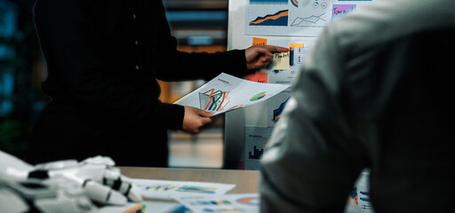 Team members engage in a data analysis session, discussing charts and graphs in a modern office setting, emphasizing collaboration and strategic planning.Noogenesis