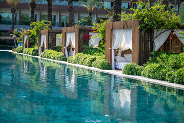 Luxury Lounger with white curtains and pool view 