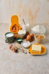 Prepared ingredients for making  pumpkin buns with cinnamon on light sand concrete background. Pumpkin recipes.