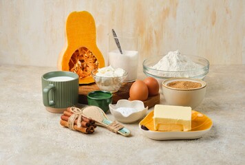 Prepared ingredients for making  pumpkin buns with cinnamon on light sand concrete background. Pumpkin recipes.