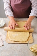 Step by step cooking pumpkin buns on light concrete background. Rolling out dough on wooden board. Step by step recipes.