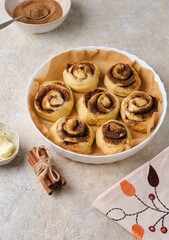 Step by step preparation of pumpkin buns on a light concrete background. Formed pumpkin cinnabons in a ceramic mold before baking.