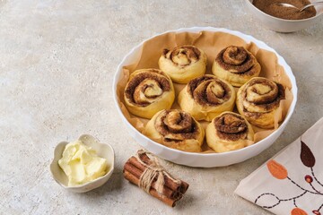 Step by step preparation of pumpkin buns on a light concrete background. Formed pumpkin cinnabons in a ceramic mold before baking.